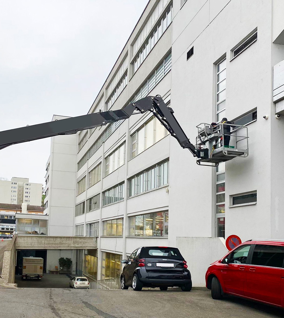 Mitarbeiter auf einer Hubarbeitsbühne bei Arbeiten an einer mehrgeschossigen Gebäudefassade