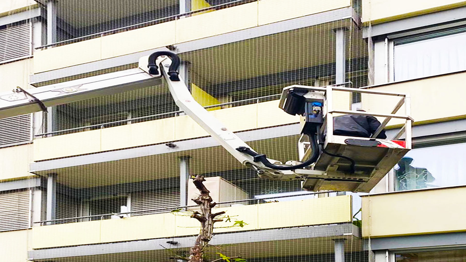 Hebebühne bei Montagearbeiten an einem Fenster- und Storenbereich für die Vogelabwehr in Basel Land