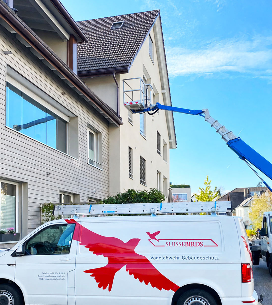 Suisse Birds Servicefahrzeug und Hubarbeitsbühne bei Arbeiten an einem Mehrfamilienhaus