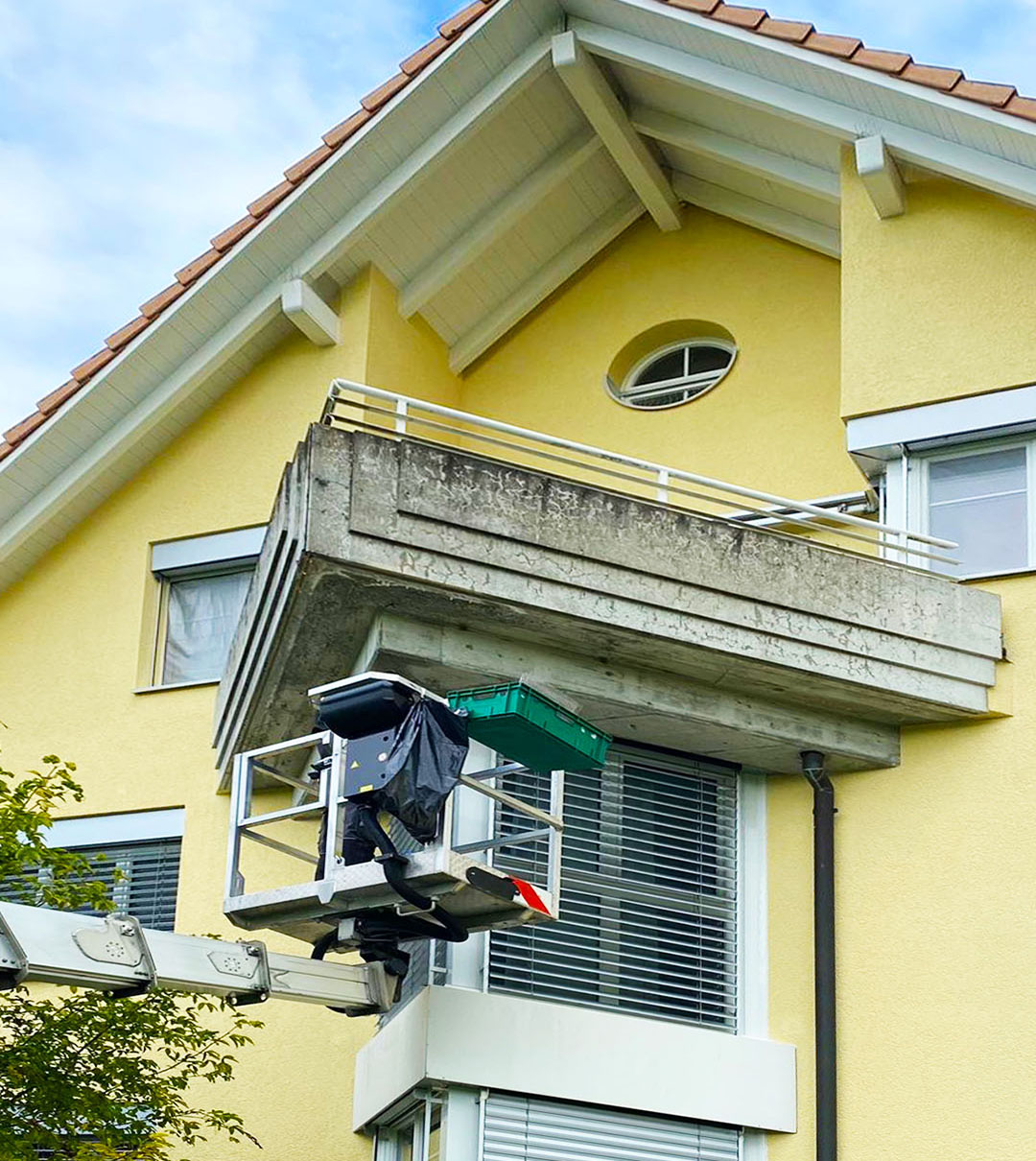 Arbeitsbühne bei Arbeiten an Balkon und Fassade eines Wohnhauses