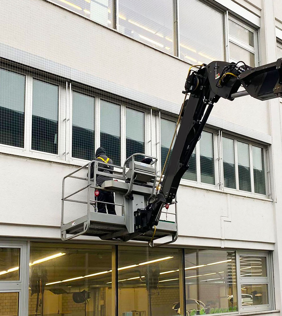 Mitarbeiter auf einer Hubarbeitsbühne bei Arbeiten an der Fassade eines Gewerbegebäudes