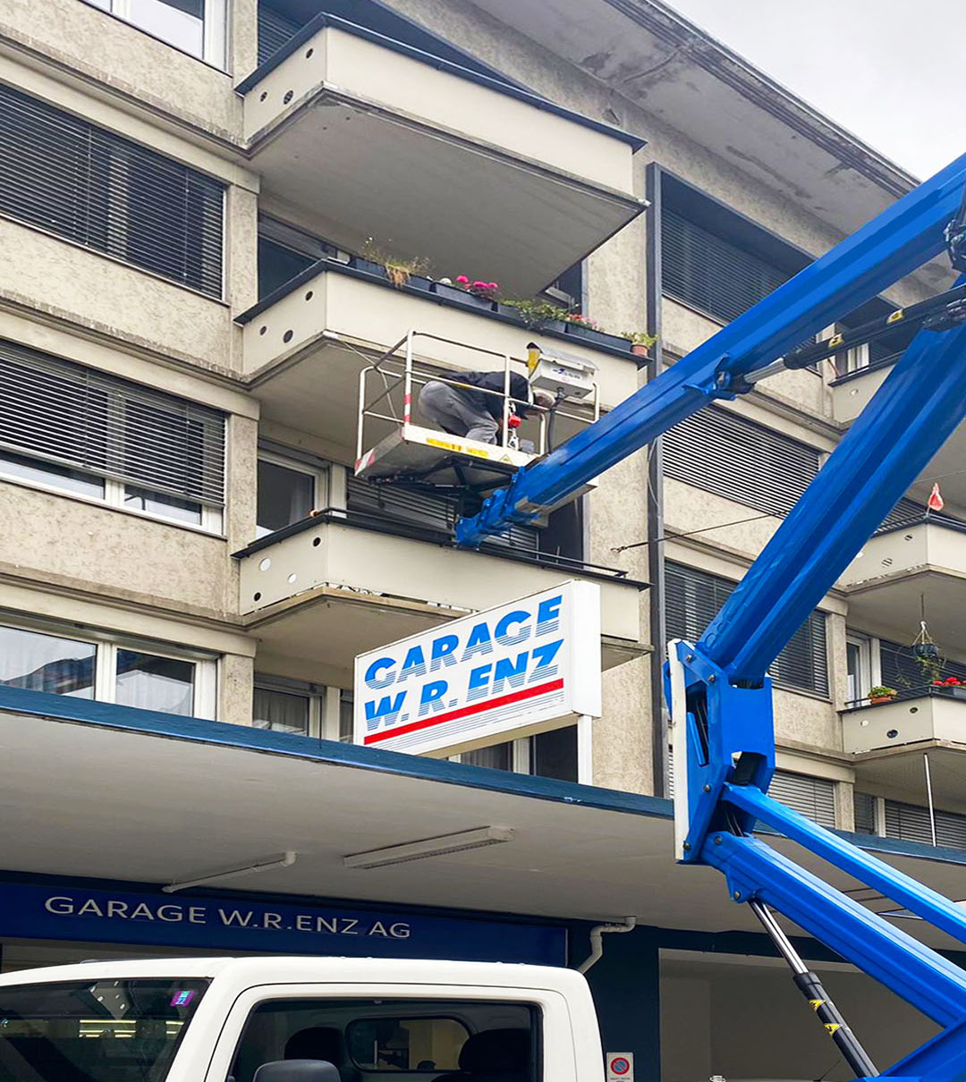 Blaue Hubarbeitsbühne bei Arbeiten an einem mehrgeschossigen Gebäude mit Gewerbeflächen