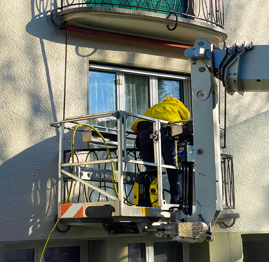 Mitarbeiter im Arbeitskorb bei Arbeiten an einer Fassade