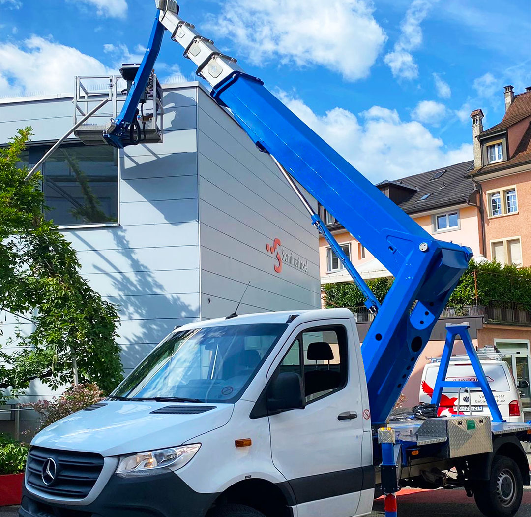 Suisse-Birds-Fahrzeug und Hubarbeitsbühne bei Arbeiten an einem Gewerbegebäude