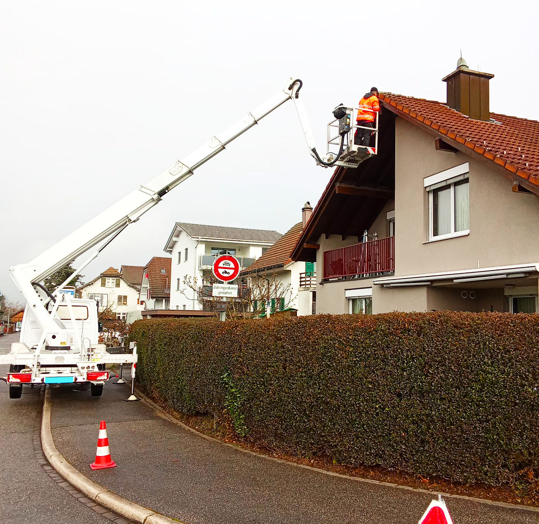 Hubsteiger bei Arbeiten an der Dachkante eines Wohnhauses