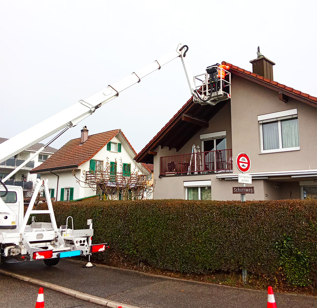 Hubsteiger bei Arbeiten an Dachkante und Giebel eines Wohnhauses