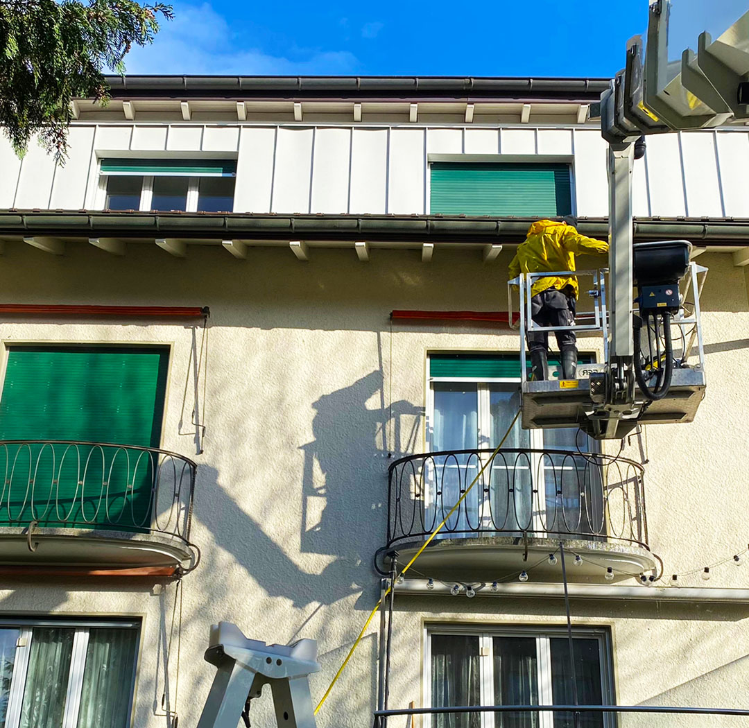 Mitarbeiter auf einer Arbeitsbühne bei Arbeiten an einem Balkon