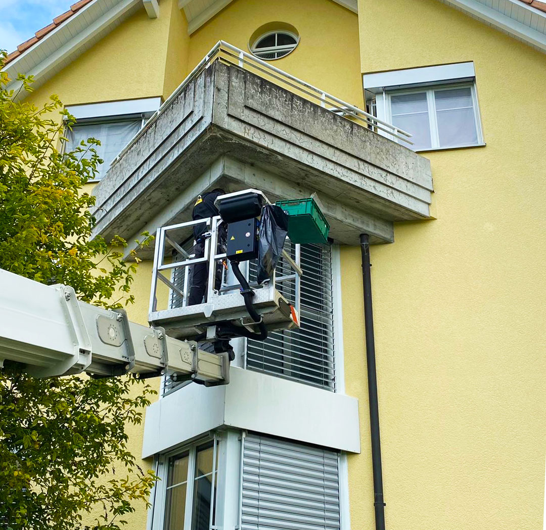 Mitarbeiter im Arbeitskorb bei Arbeiten an einer Wohnhausfassade