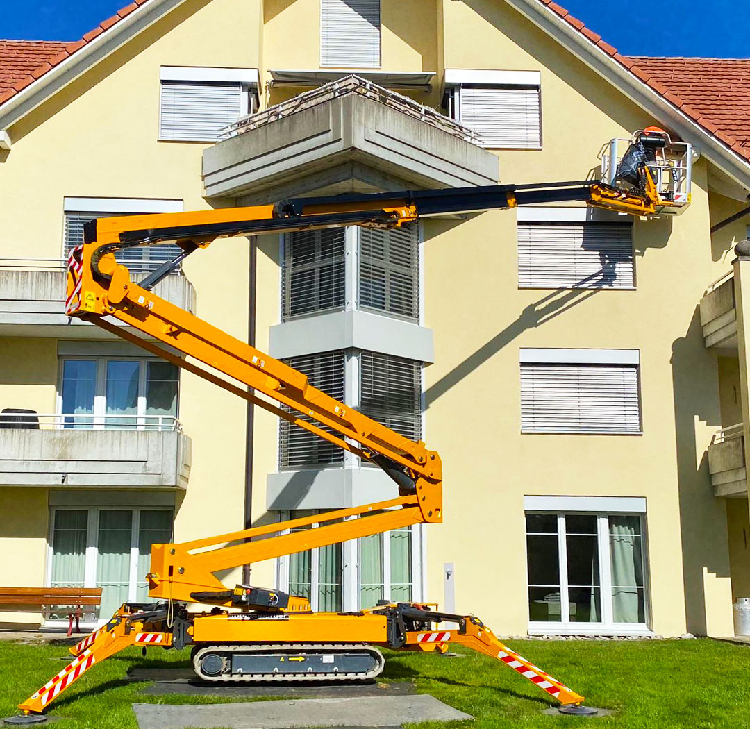 Raupenarbeitsbühne bei Arbeiten an Balkon und Fassade eines Wohnhauses
