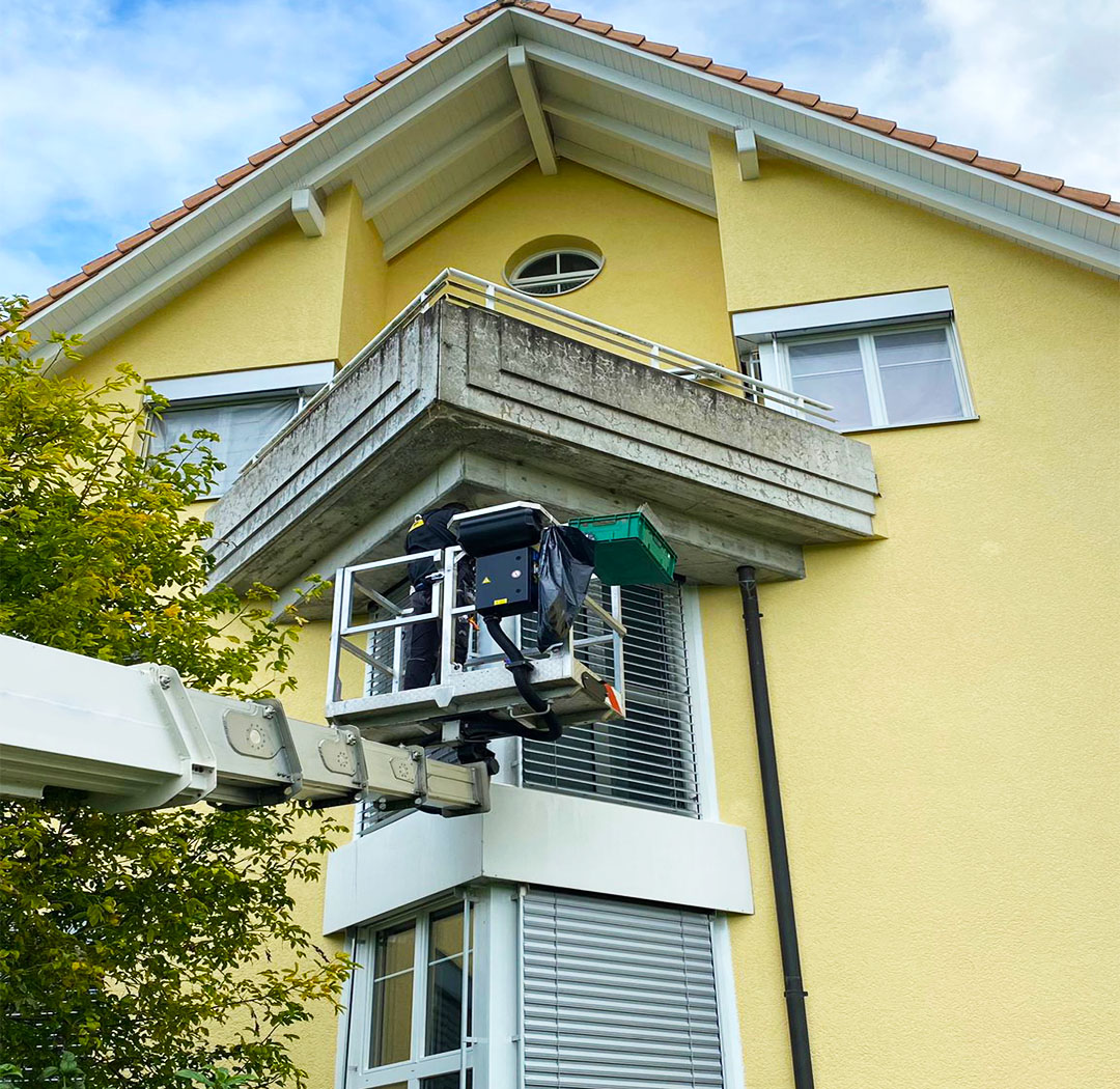 Mitarbeiter auf einer Hebebühne bei Arbeiten an einem Wohnhaus