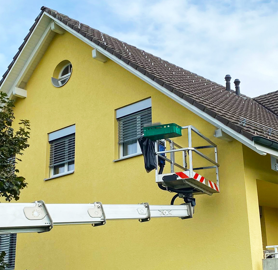 Mitarbeiter auf einer Arbeitsbühne bei Arbeiten an einem Einfamilienhaus