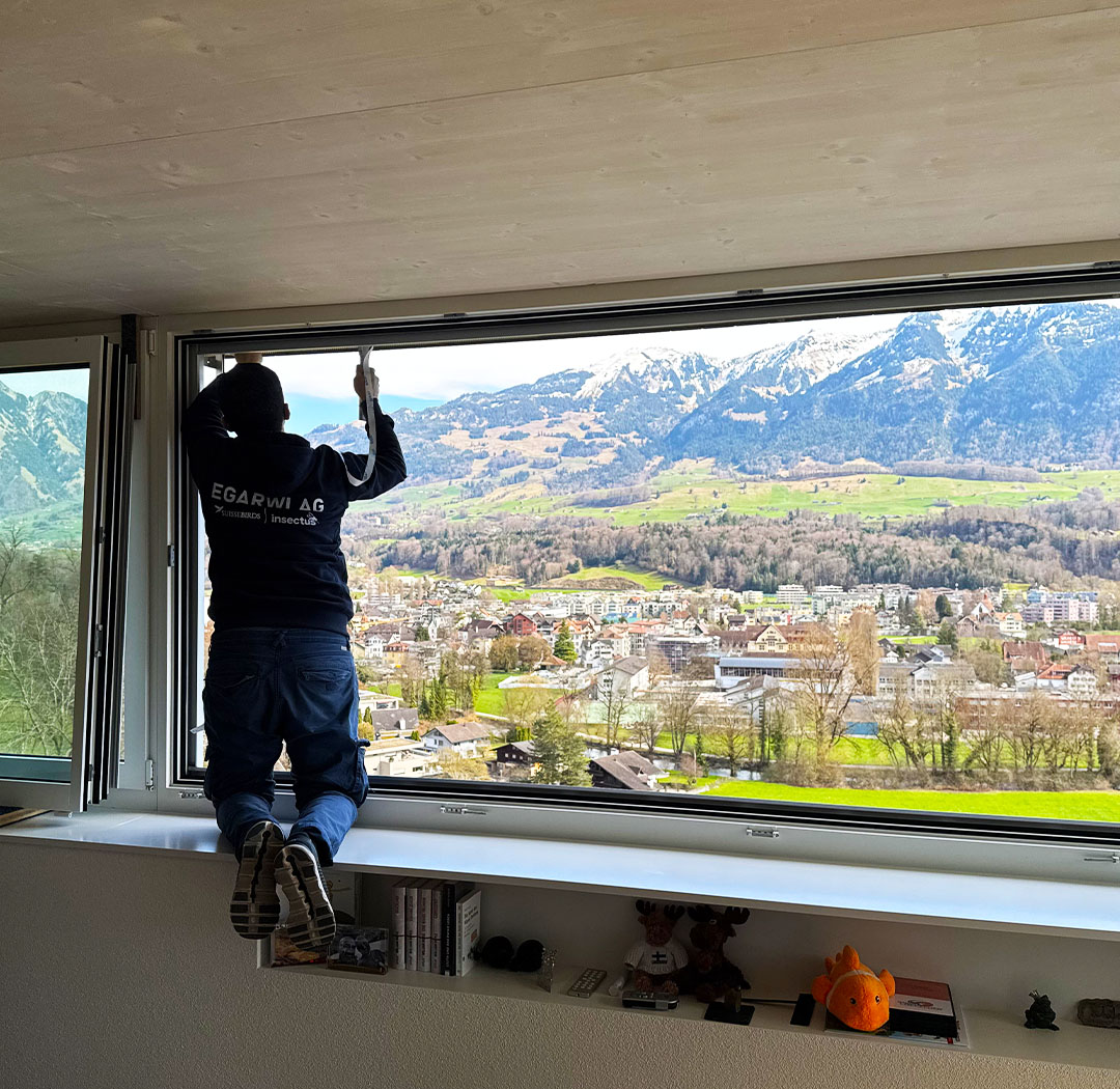 Mitarbeiter bei Arbeiten an einem Storenkasten vor einer grossen Fensterfront