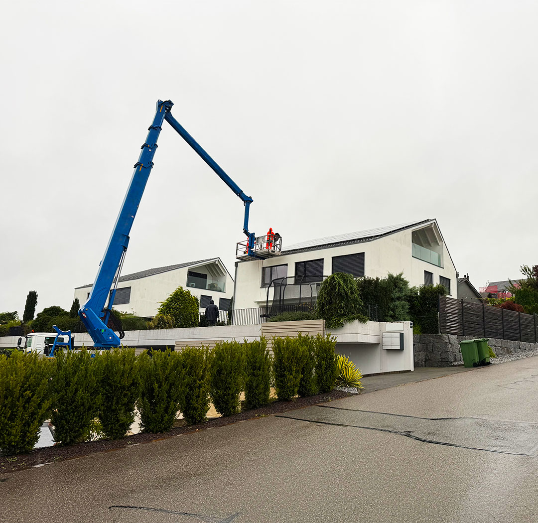 Hubarbeitsbühne bei Arbeiten an Dach und Fassade eines modernen Wohnhauses