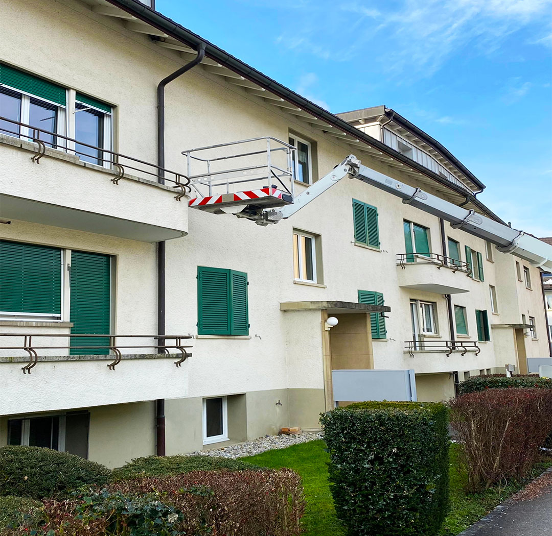 Suisse-Birds-Fahrzeug vor einem Wohngebäude mit Fassaden- und Dachbereichen