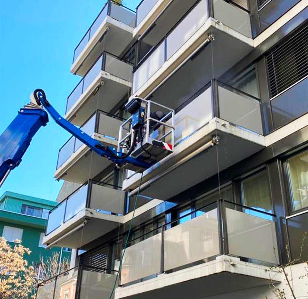 Mitarbeiter auf einer Hubarbeitsbühne bei Arbeiten an einer Balkonfassade